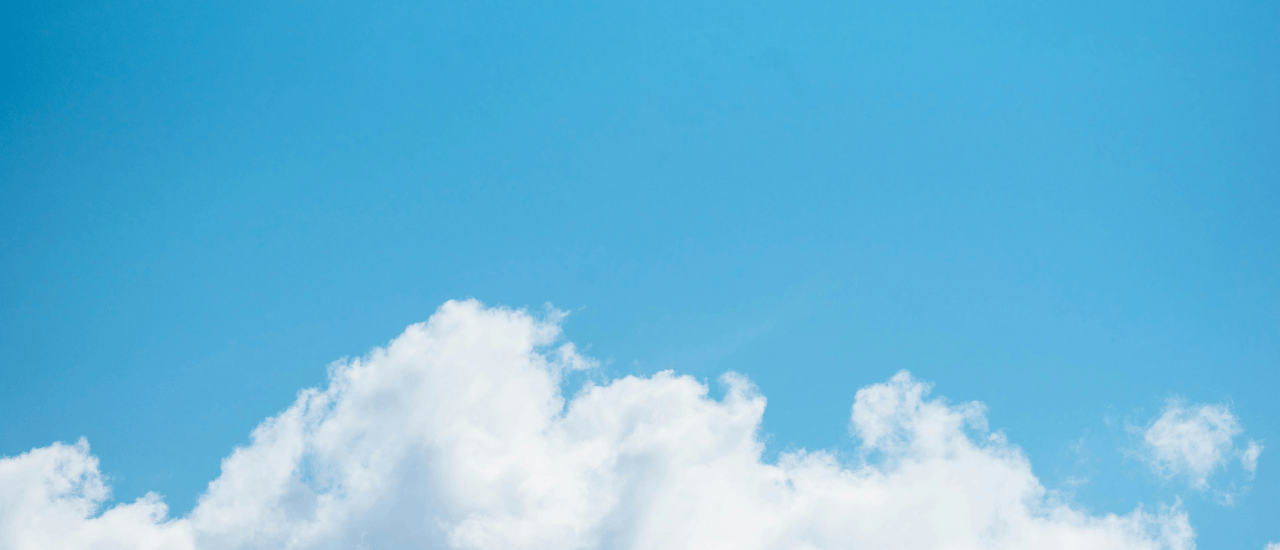 Bright blue sky with fluffy white clouds along the bottom edge, creating a calm and clear daytime scene.