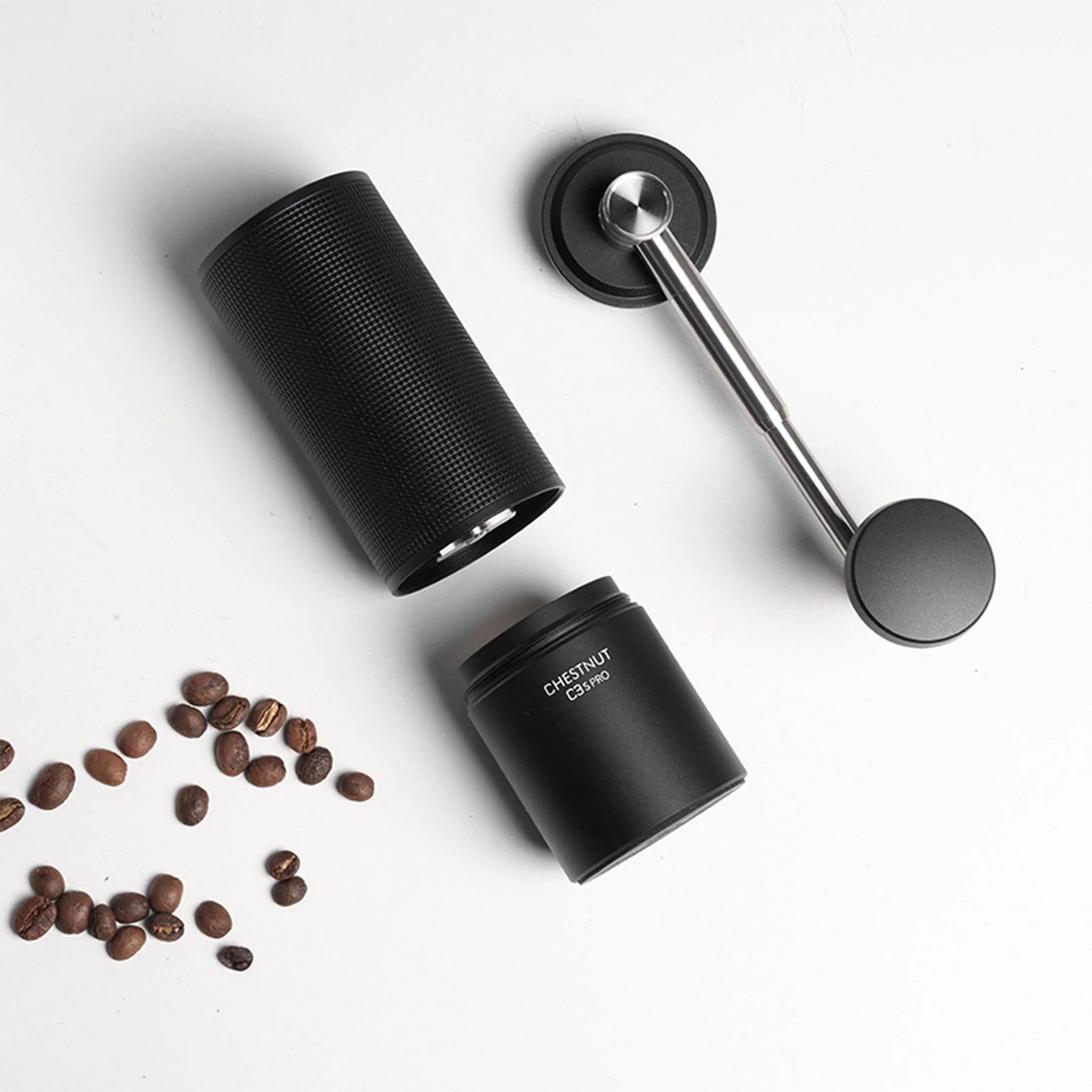 Timemore Chestnut C3S Pro manual coffee grinder disassembled with handle and coffee beans on white background.