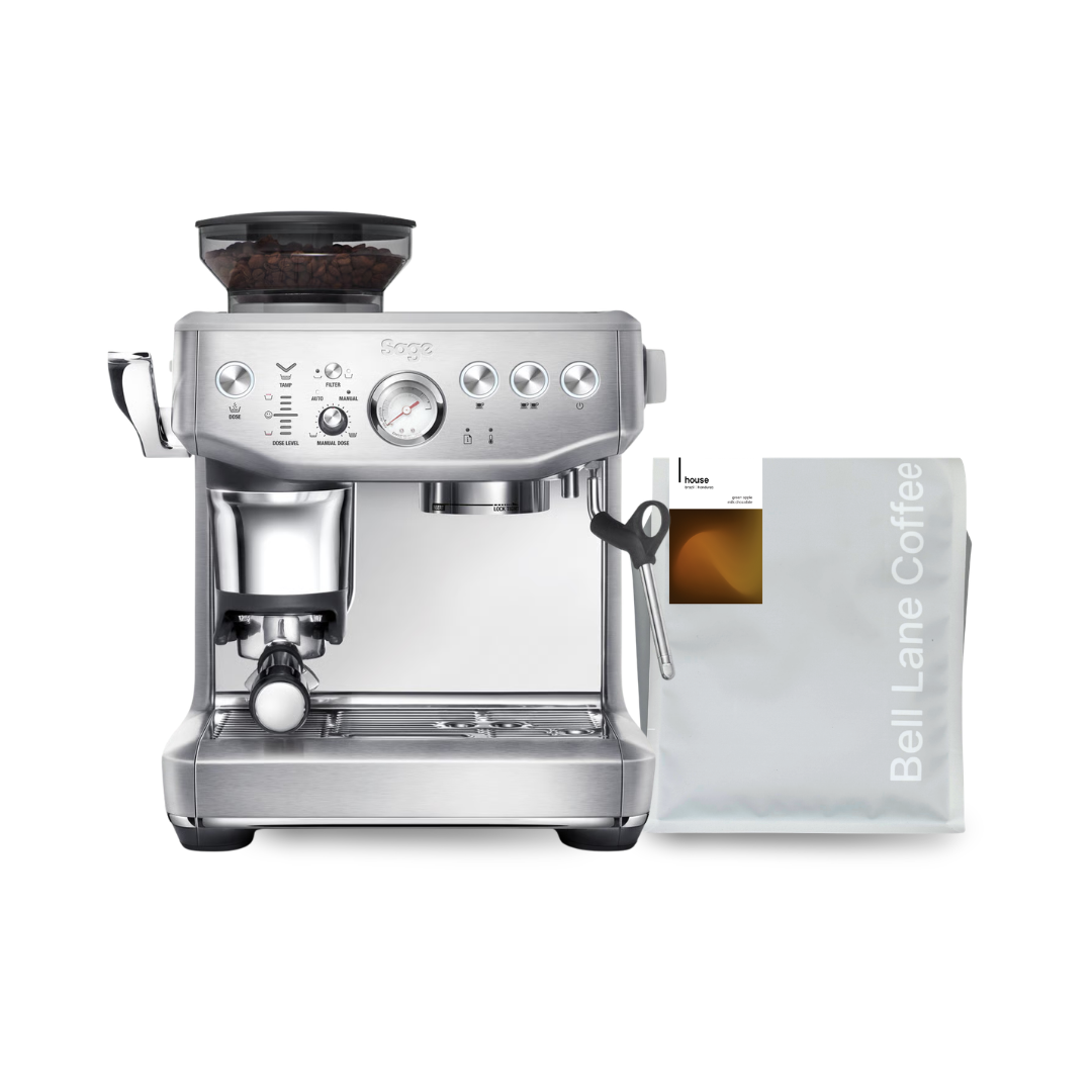A silver Breville espresso machine with a dark bean hopper on top, shown next to a white bag of Bell Lane Coffee on a plain white background.