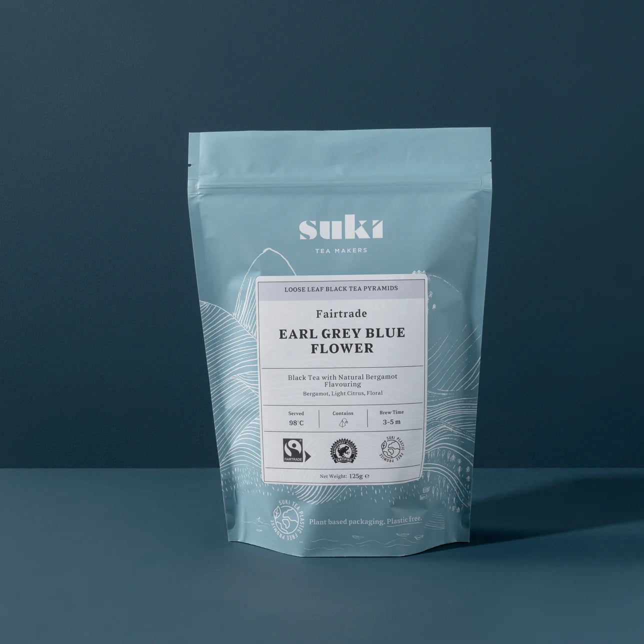 Bag of Suki Tea Makers Fairtrade Earl Grey Blue Flower tea, featuring light blue packaging with white illustrated mountains and a label describing the tea as black tea with natural bergamot flavouring.